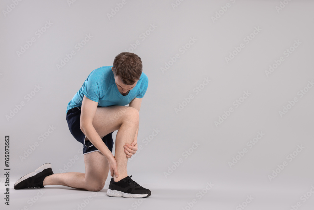 Obraz premium Man suffering from leg pain on grey background. Space for text
