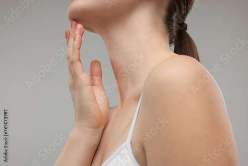 Woman touching her chin on grey background, closeup