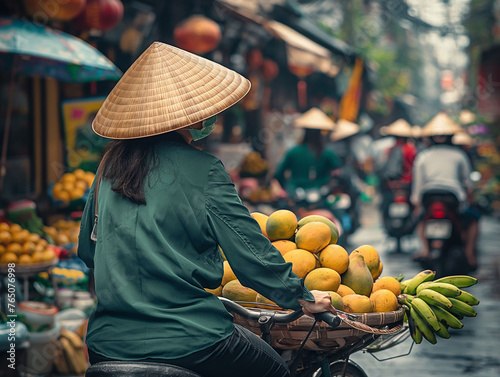 Vietnamese street vendor on the bicycle, wearing the Vietnamese hat, in Hanoi and Saigon. The woman selling her fruits on bicycle.