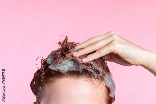 Young woman washing her hair with shampoo on pink background, closeup. Space for text