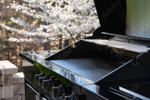 Backyard garden view with a black gas grill in springtime. Closeup shot. Outdoors cooking concept.