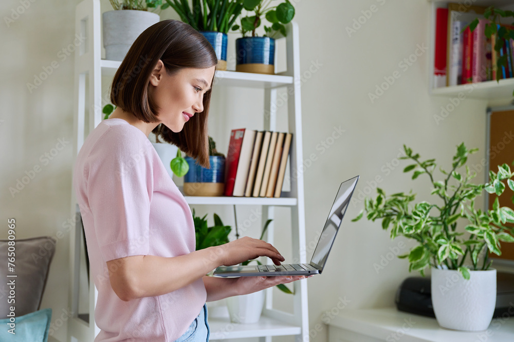 Young woman using laptop in living room home interior Young woman using laptop in living room home interior