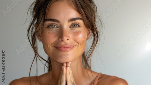 Portrait of smiling woman face with hands clasped in prayer looking on. Mockup for yoga center; healthy and mindful spiritual lifestyle. Horizontal poster, blank space for a spa advertising. Namaste