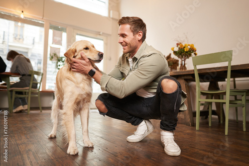 Close up portrait of happy dog owner, man with his pet giving a treat, spending time in animal-friendly cafe or co-working space