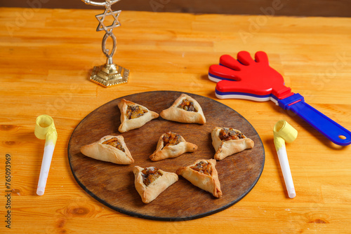 Sweet gomentashi cookies on a wooden board next to a clapper for the Purim holiday photo