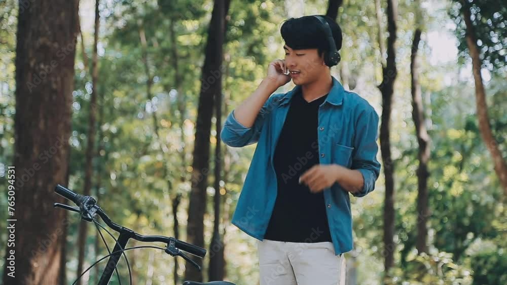 A man pushes a bicycle and walks happily to relax in the park after cycling for exercise. A man pushes a bicycle and walks happily to relax in the park after cycling for exercise.
