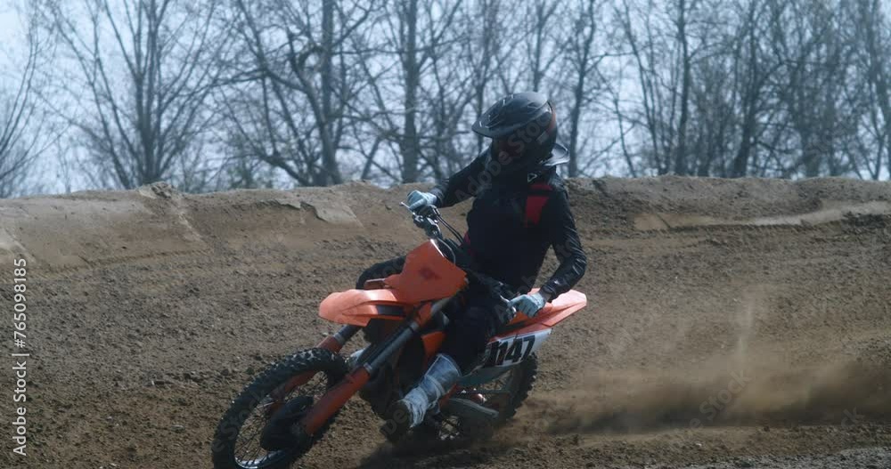 Slow motion macro of extreme sports motorbike rider is in action offroad during motocross race with dirt splashing from motorbike rear wheel. Slow motion macro of extreme sports motorbike rider is in action offroad during motocross race with dirt splashing from motorbike rear wheel.