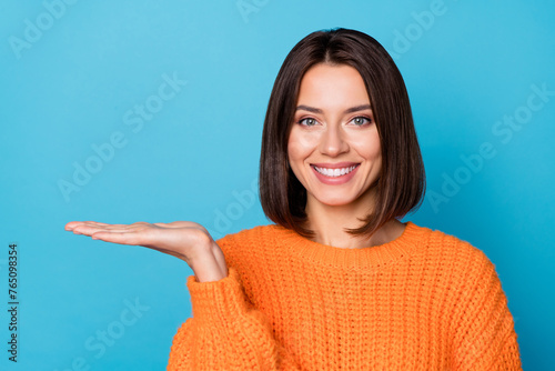 Portrait of attractive cheerful girl demonstrating holding on palm copy space ad new novelty isolated over bright blue color background