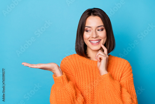 Portrait of attractive cheerful girl holding on palm copy space choosing idea isolated over bright blue color background