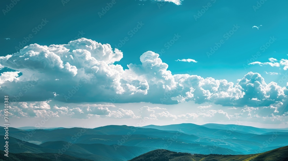 Clouds hovering over mountainous landscape - A serene mountain landscape is crowned by bountiful, fluffy clouds against a clear, blue sky, evoking a sense of calm