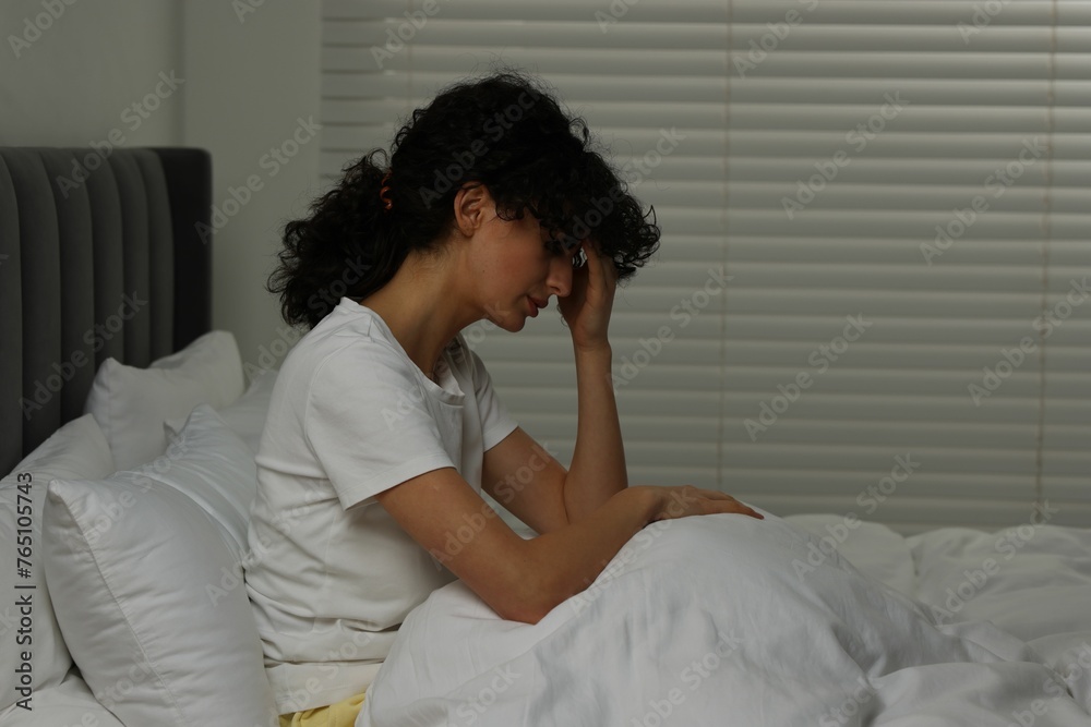 Young woman suffering from headache in bed at night
