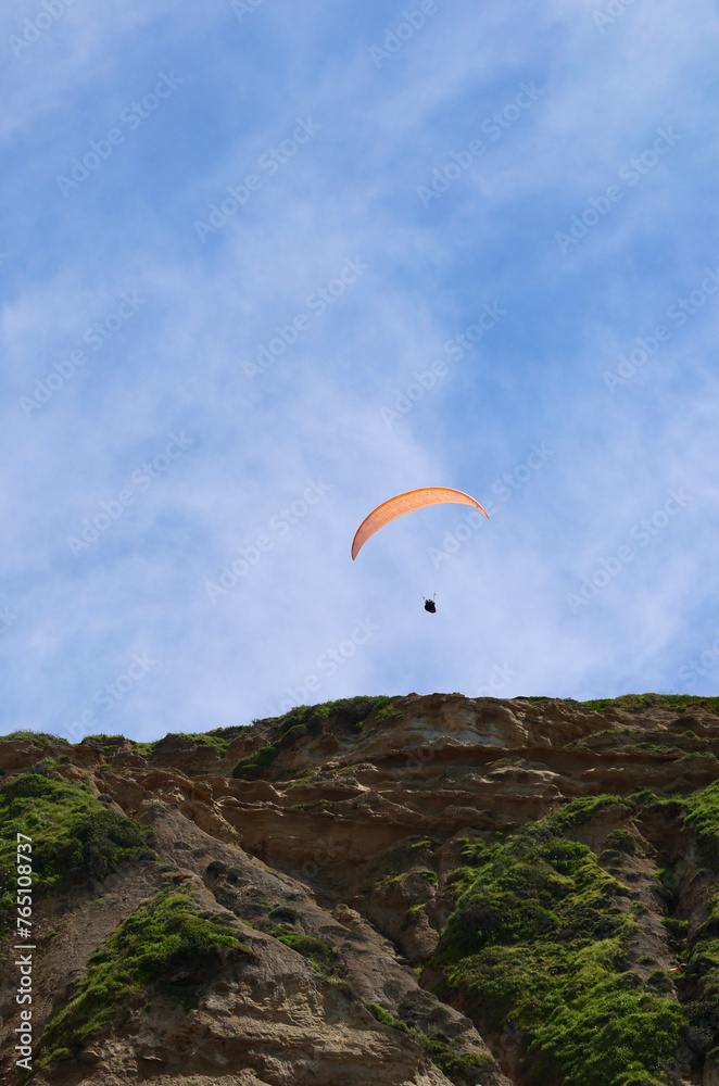 paraglider soaring above the coastline paraglider soaring above the coastline