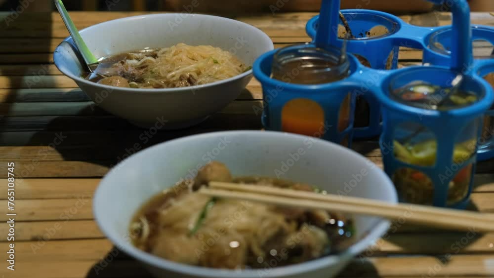 Woman eating freshly made Guay teow noodle soup with beef and bean sprouts in traditional Thai cafe, slow motion Woman eating freshly made Guay teow noodle soup with beef and bean sprouts in traditional Thai cafe, slow motion