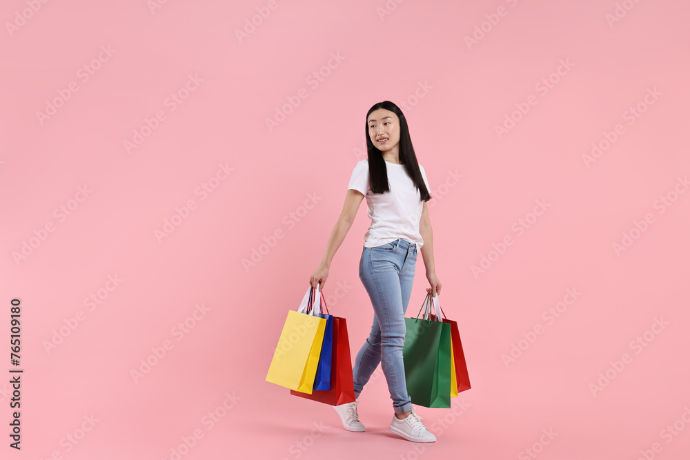 Smiling woman with shopping bags on pink background. Space for text