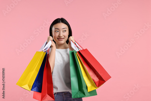 Happy woman with shopping bags on pink background. Space for text