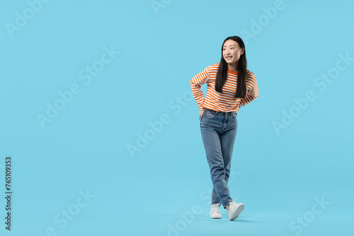 Full length portrait of smiling woman on light blue background. Space for text