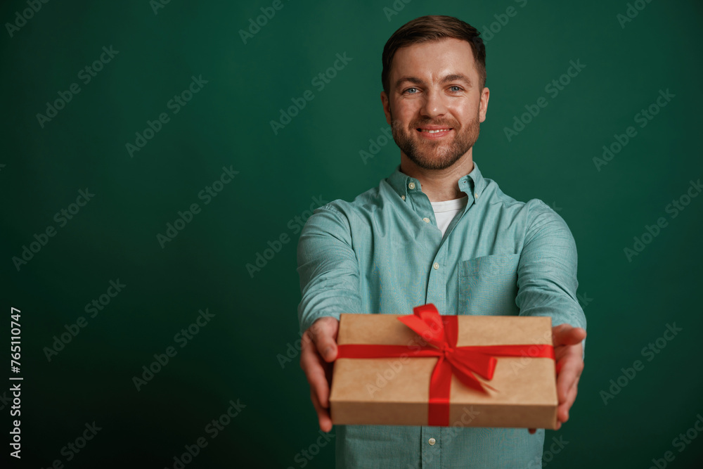 Conception of holidays, with gift box. Man is standing against background in the studio