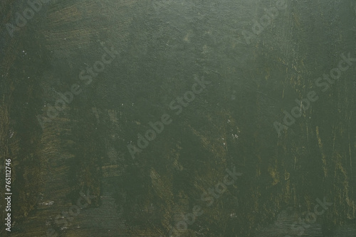 Old textured wall unevenly painted with green paint with stains and scratches