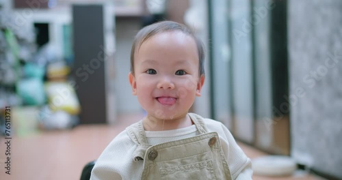 A baby toddler child is looking at the camera with a smile on its face and spit saliva from her mouth