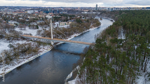 Drone photography of a footbridge going over river from city to public park during winter day