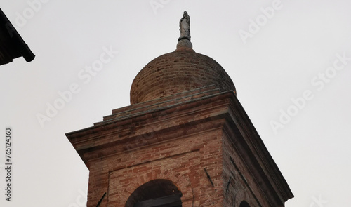 Campanile di una chiesa visto dal basso che si staglia nel cielo grigio autunnale