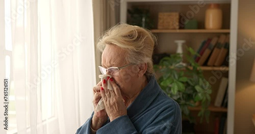 Senior woman blowing her nose indoors