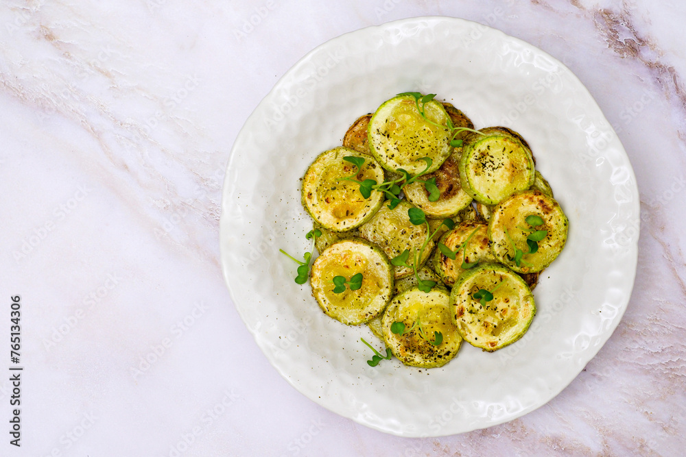 Fried zucchini with lemon zest and thyme on white background. Top view.