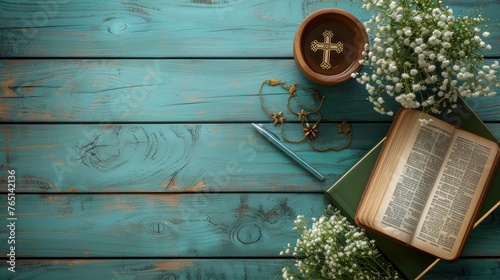 an open book with a cross on top of it next to a vase of flowers and a knife on a blue wooden table. photo