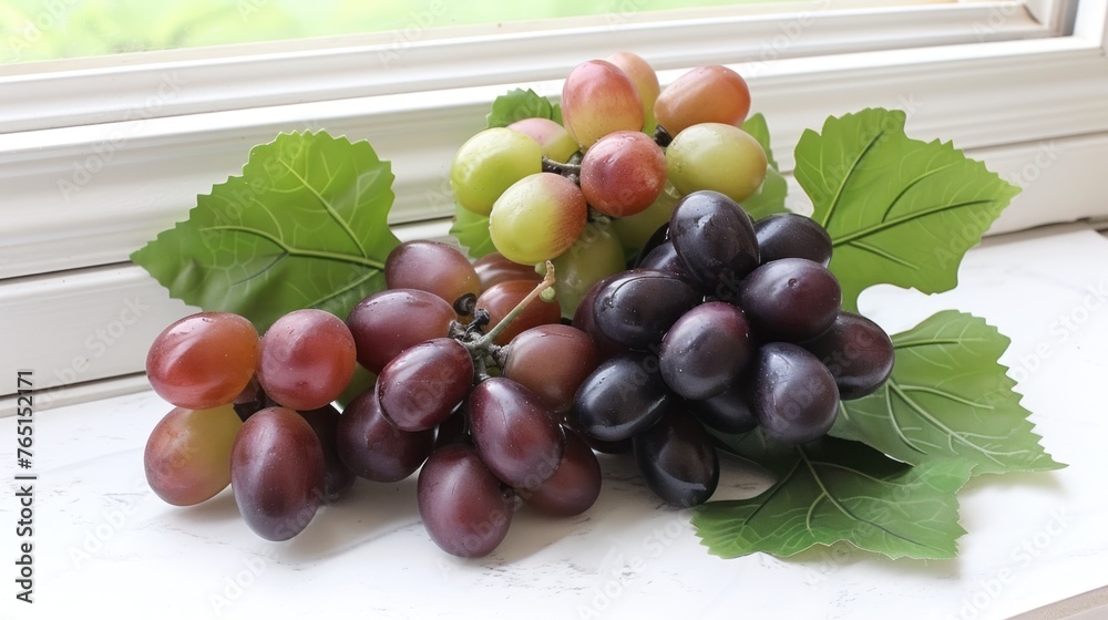 a bunch of grapes sitting on top of a window sill next to a leafy green leafy plant.
