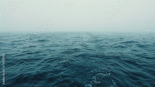 a large body of water with a foggy sky in the background and a few small waves in the foreground.