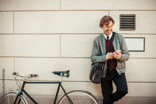 Mature man taking a break from cycling and using a phone while commuting to work