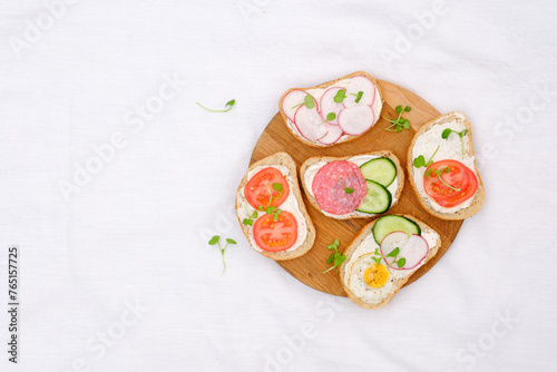 Different tapsas sandwiches with vegetables on board on white background. top view.