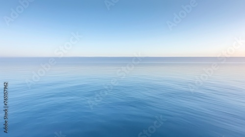 a large body of water with a bright blue sky in the background and a few small waves in the foreground. © Alice
