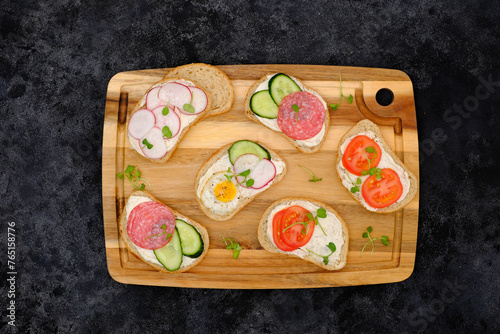 Different tapsas sandwiches with vegetables on cutboard on dark background. top view.