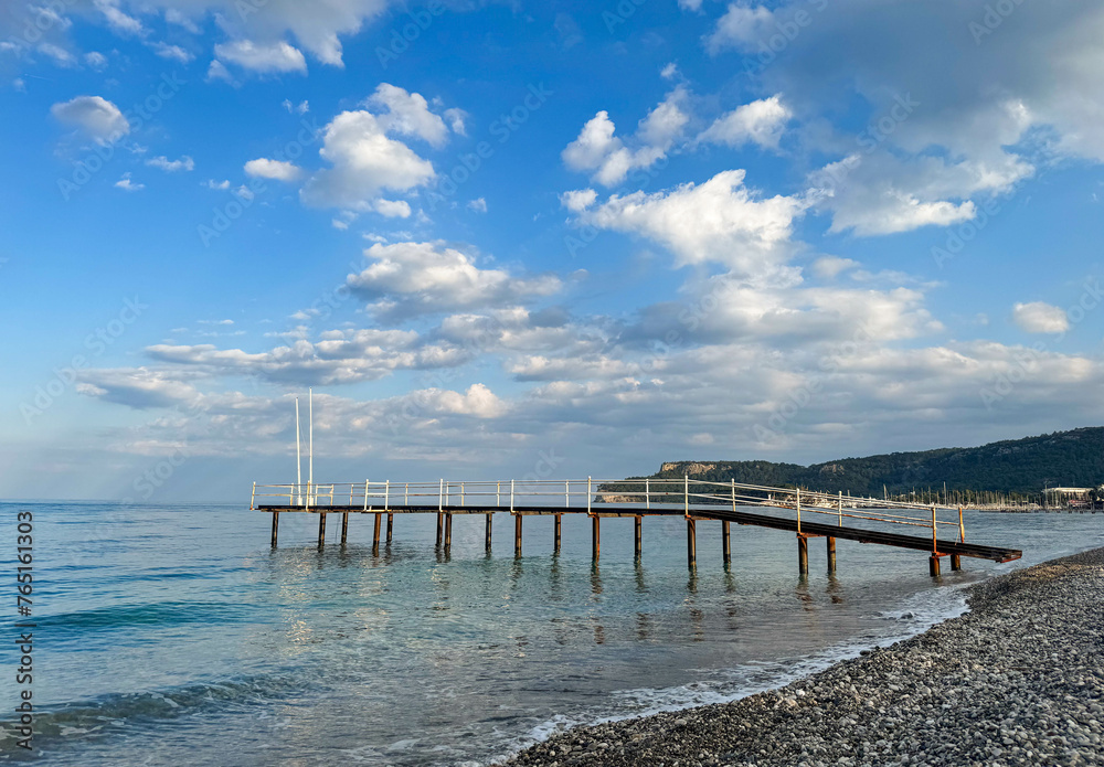 Seascape, landscape on a sunny summer cloudless day, pier. Calm sea, mountains and pebble beach, Turkey, Antalya, Kemer.