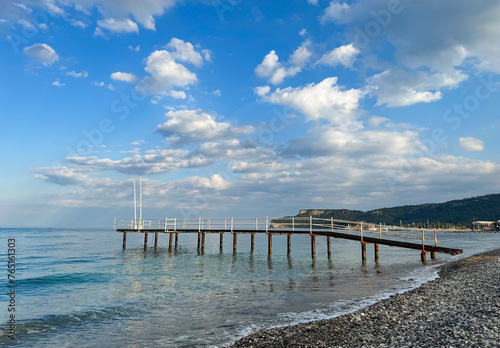 Seascape, landscape on a sunny summer cloudless day, pier. Calm sea, mountains and pebble beach, Turkey, Antalya, Kemer. © Ekaterina