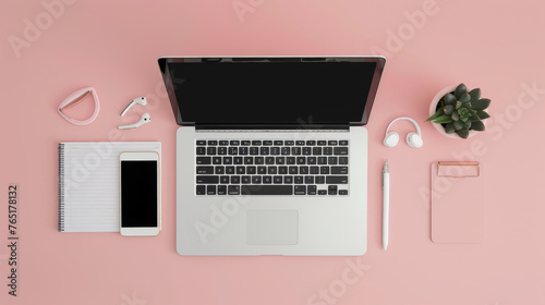 A neatly organized desk with a laptop, smartphone, notebook, and accessories on a pink surface.