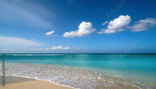 A beautiful beach with a blue ocean and white clouds in the sky. The ocean is calm and the waves are small. The beach is empty and peaceful