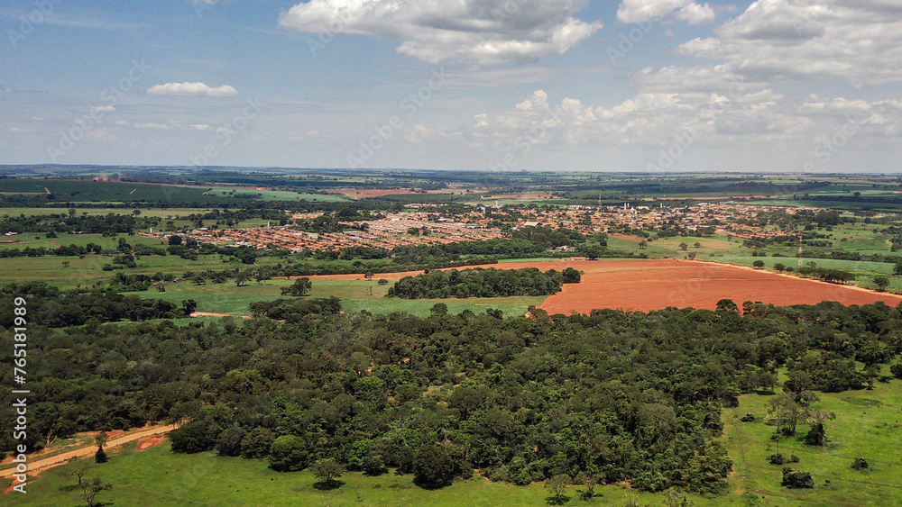 Vista aérea de drone da cidade de Guaraci/SP, em dia ensolarado com áreas rurais e mata nativa em primeiro plano