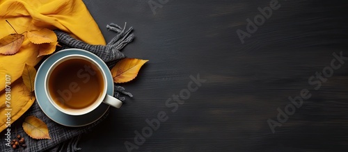 Tea, autumn leaves, and scarf on dark surface