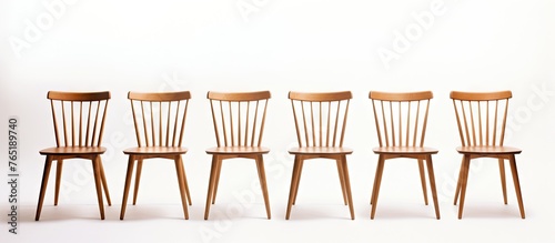 Four wooden chairs arranged against a white wall