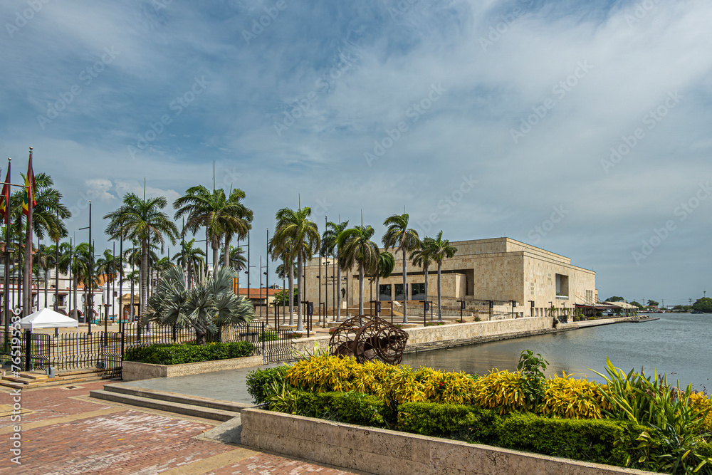 Cartagena, Colombia - July 25, 2023: Modern convention center building borders historic old town port under blue cloudscape. Palm trees and plants