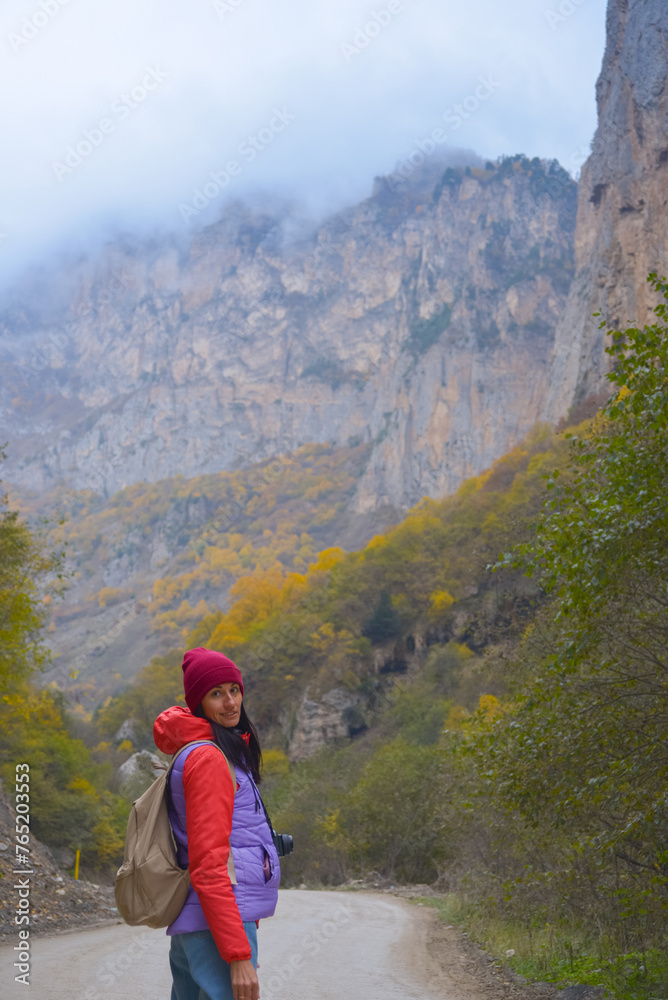 Woman traveler on a winding road in the mountains on a foggy autumn day