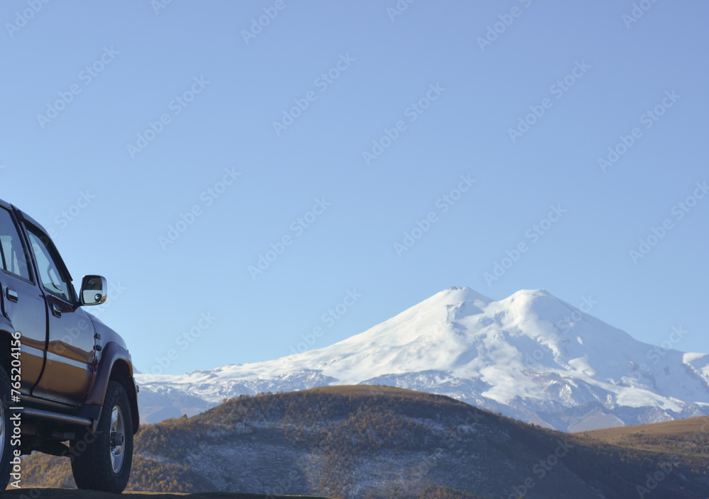 Travel concept with big 4x4 car against sunset and mountains. Closeup photo of offroad wheel