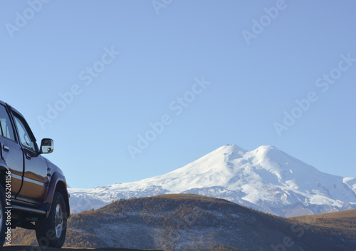 Obraz na płótnie Travel concept with big 4x4 car against sunset and mountains. Closeup photo of offroad wheel w salonie