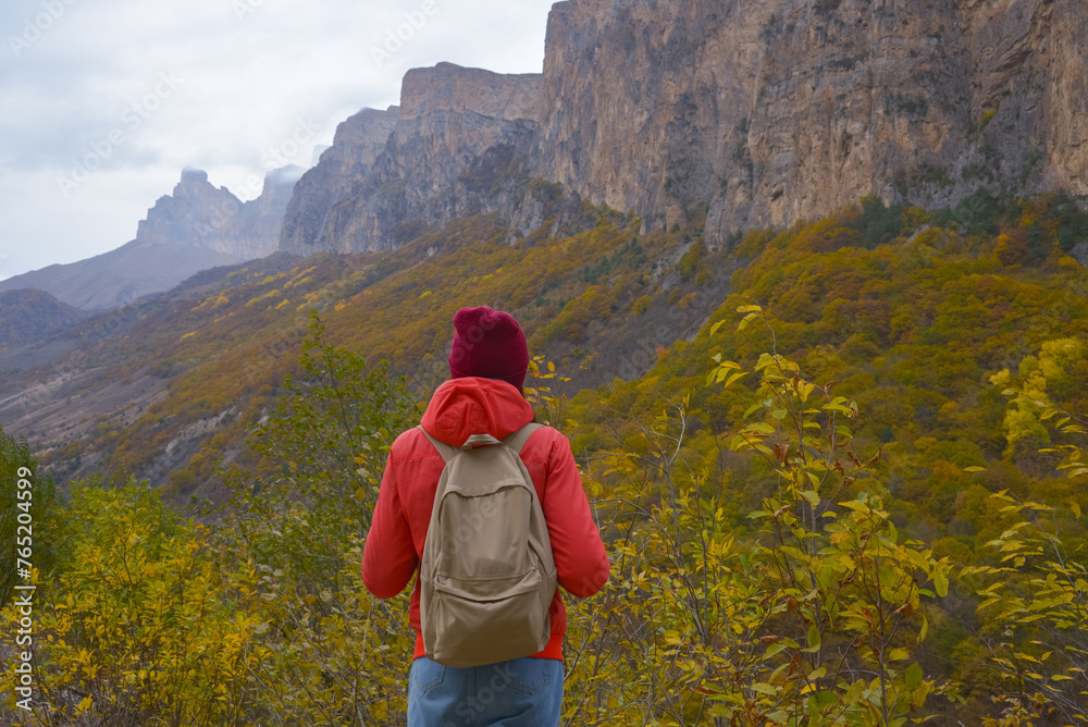 Brunette woman with a backpack on her back outdoors exploring the Caucasus Mountains in Russia, traveling, lifestyle, hiking, active autumn holidays, hiking