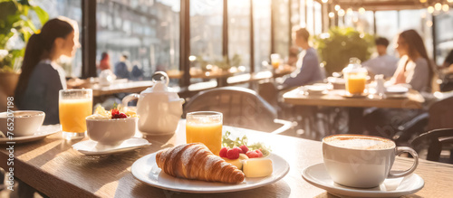 Fototapeta Naklejka Na Ścianę i Meble -  Im Vordergrund ein Croissant, im Hintergrund ein Cafe mit Gästen 