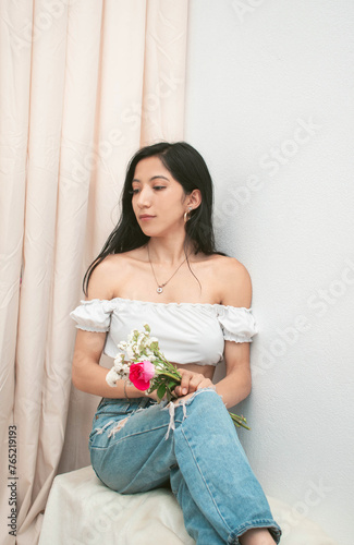 Foto Mujer delgada caucasica con blusa blanca y flores color rosado sentada represent