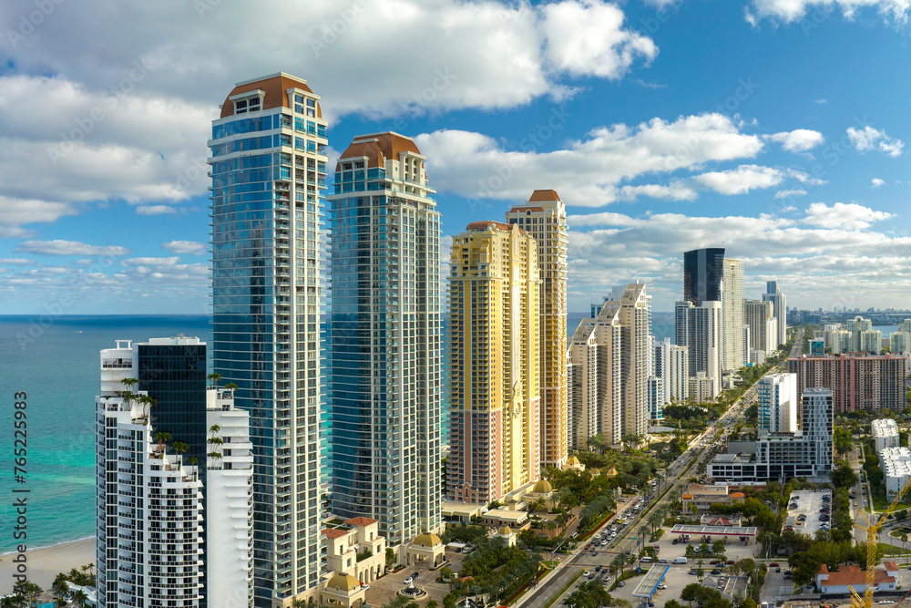 Naklejka premium View from above of luxurious highrise hotels and condos on Atlantic ocean shore in Sunny Isles Beach city. Urban street with busy traffic. American tourism infrastructure in southern Florida