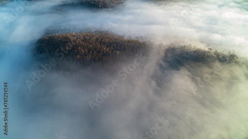 Aerial view above the clouds over forest and lakes at sunrise